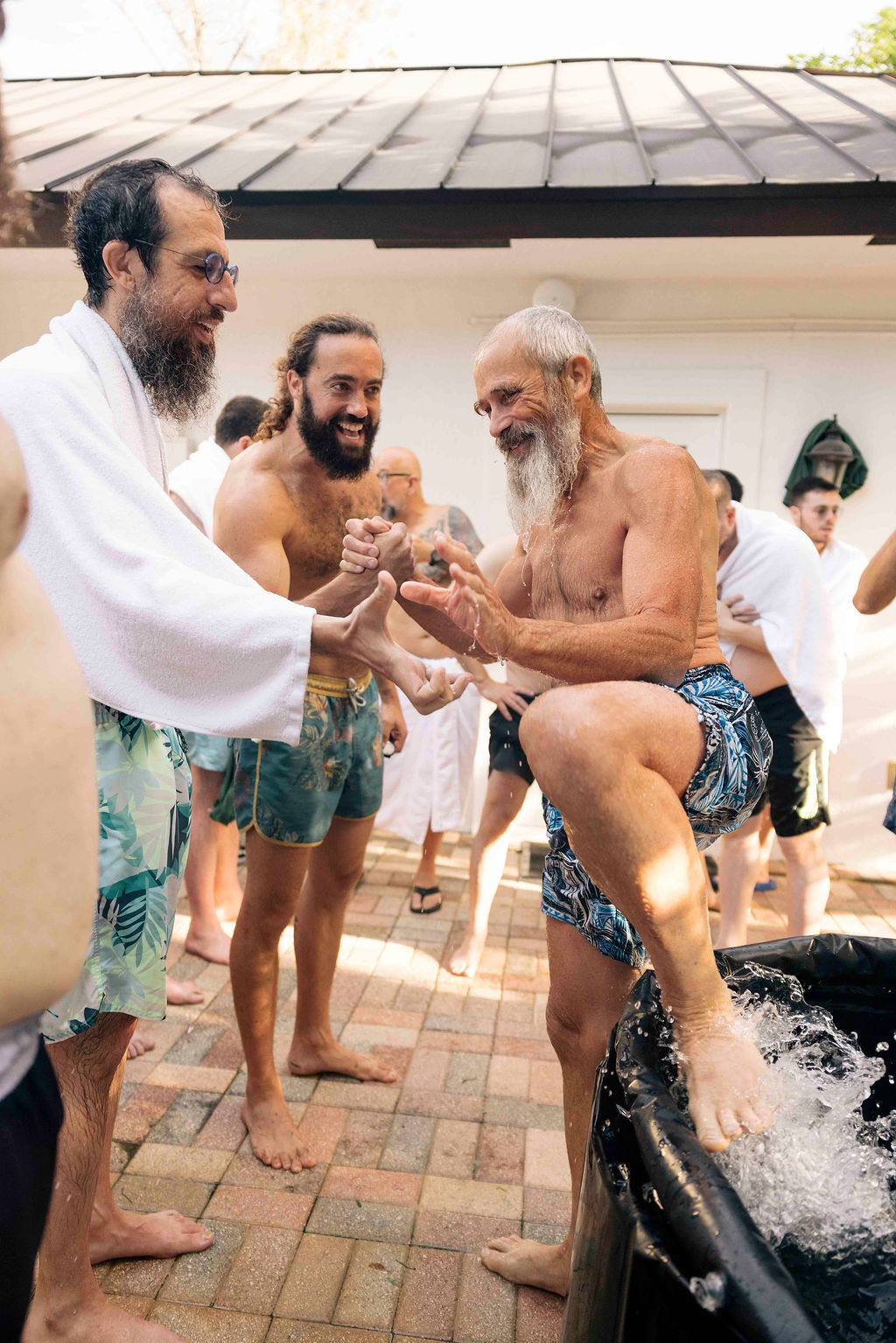 Men supporting one another during a cold plunge